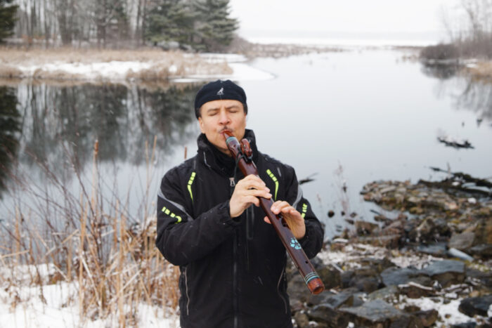 Wade Fernandez performing music on a lakeshore