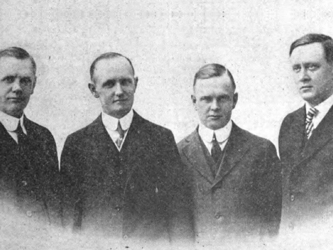 A black and white photograph of William Davidson, Walter Davidson, Arthur Davidson and Bill Harley. All four men have serious are wearing suits and ties.