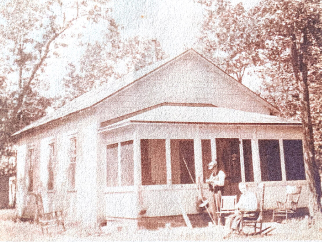 A black and white photograph of Carrie and her father in front of a large white house.