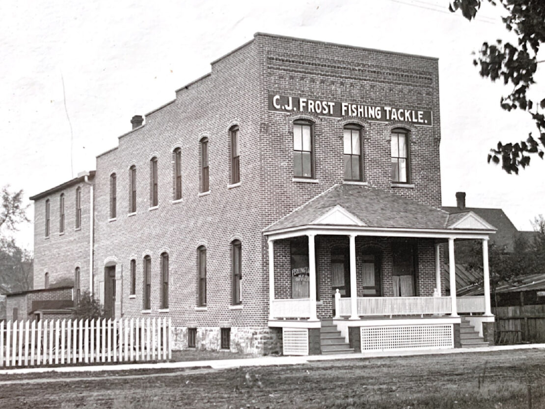 A black and white photo showing a brick building with C.J. Frost Fishing Tackle on it.