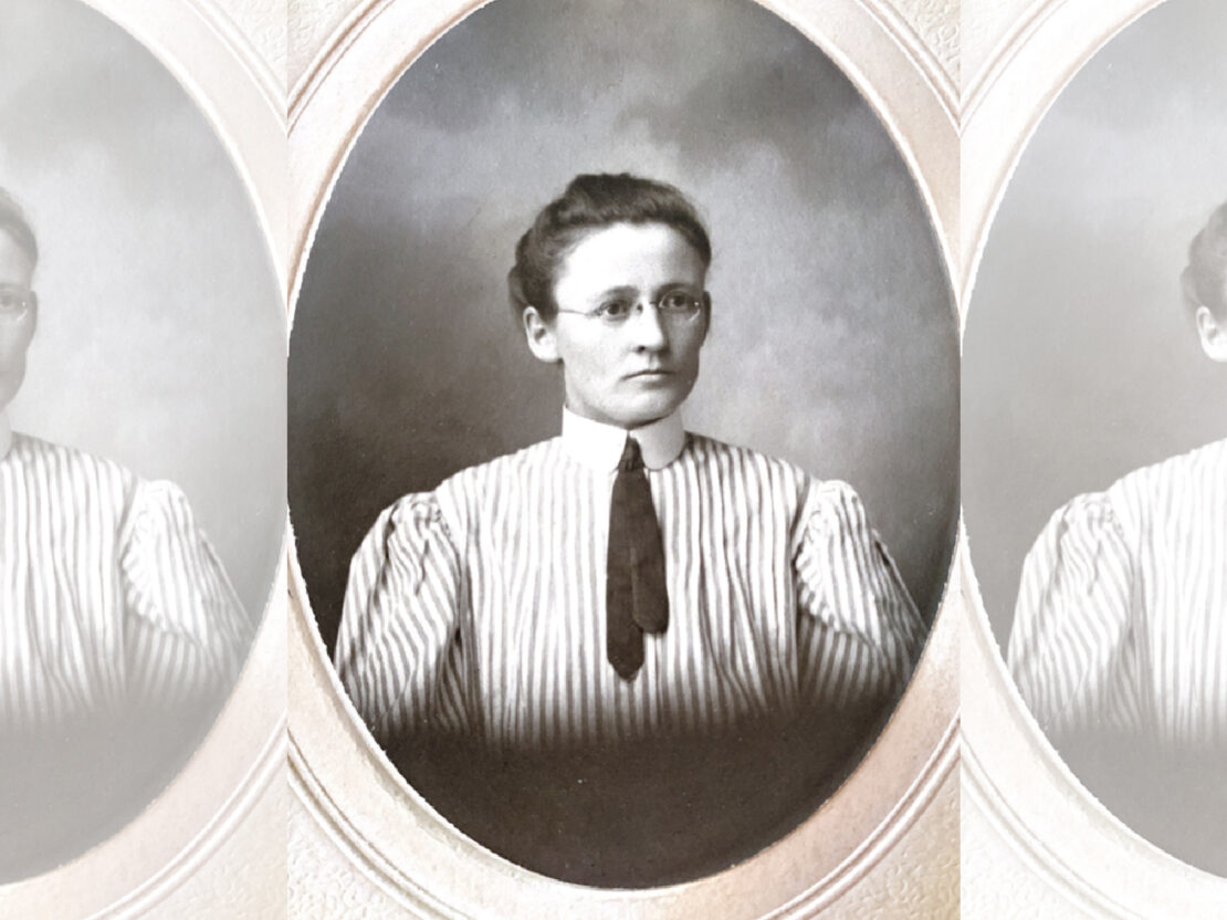 A black and white portrait of Carrie in an oval frame. Carrie’s head and shoulders are visible and she looks to the right of the viewer.
