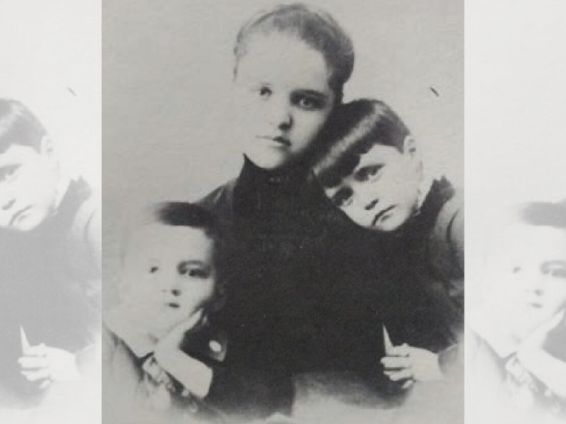 A black and white photograph showing Theda Clark with her two younger siblings, Caroline and Charles. In the photo all three are looking directly towards the viewer with their mouths closed.