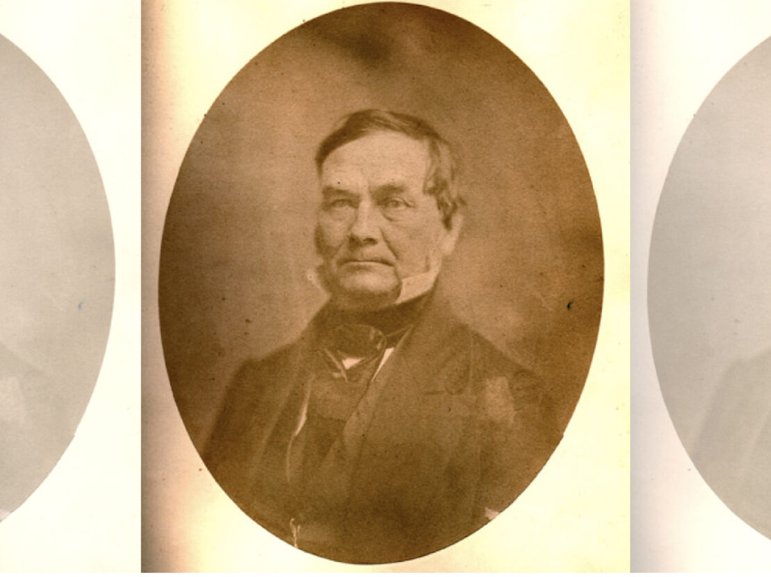 A gold-tinted black and white photograph of Henry Baird. In it his head and shoulders are visible. He wears a suit jacket and collared shirt with a tie. He looks to the left of the viewer and his lips are closed in a serious expression.