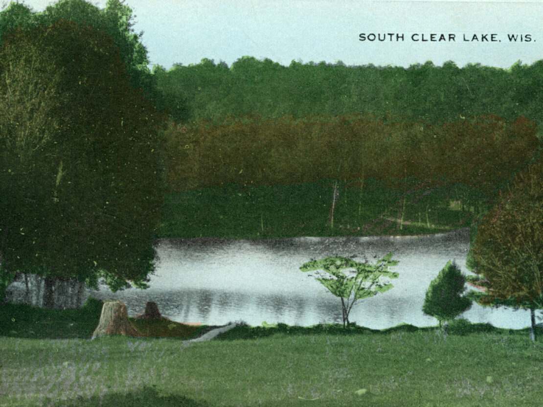 A color postcard image labeled with the text, “South Clear Lake, Wis.” showing trees surrounding a lake, and a grassy shoreline.