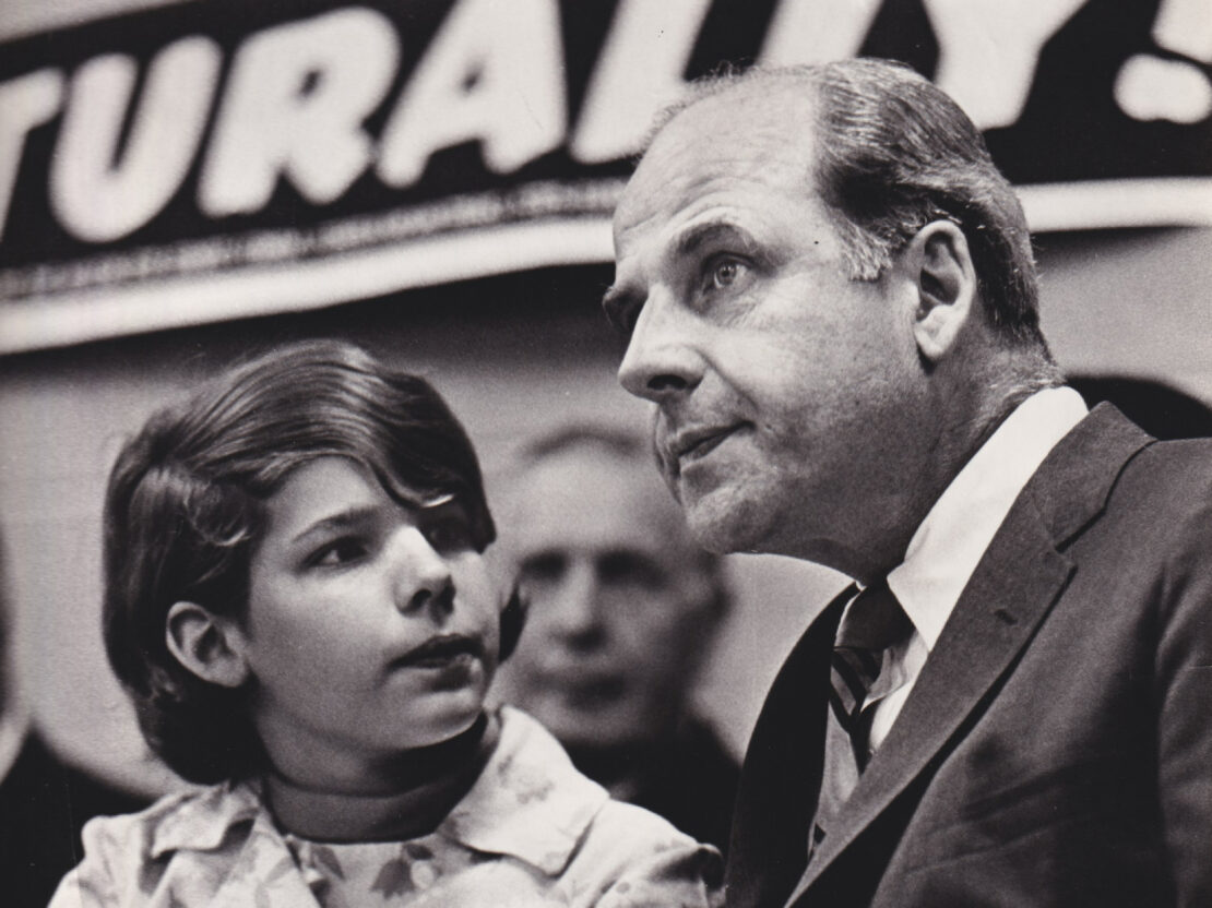 A black and white image showing Gaylord Nelson next to his daughter Tia, who is looking at him.