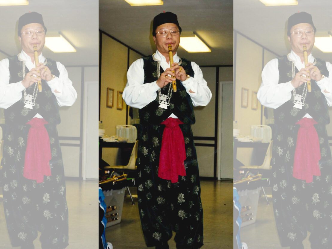 A color image showing Joe Bee playing an instrument in an indoor space.