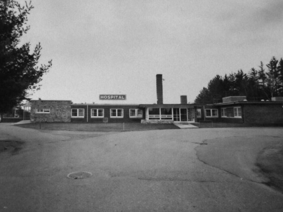 A black and white image of a building with windows and a sign reading "HOSPITAL."