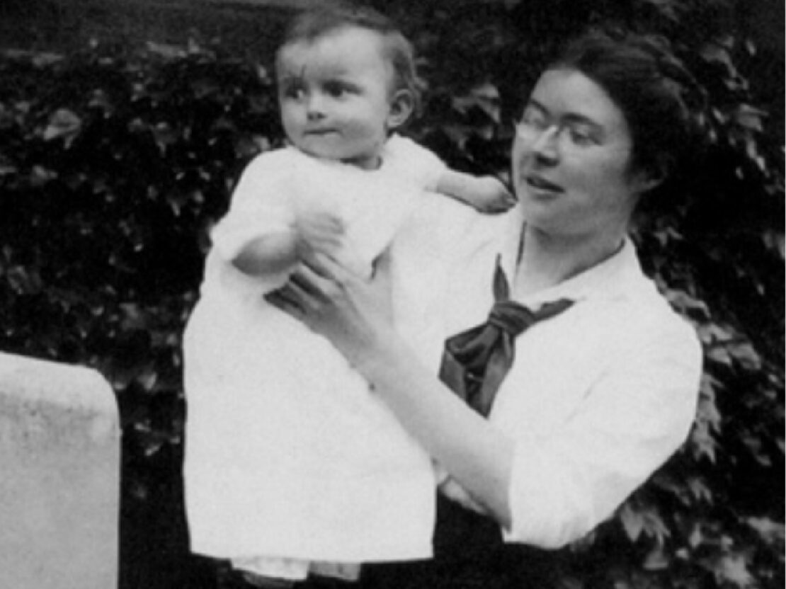 A black and white photograph of Kate holding a young child who is standing on her lap.