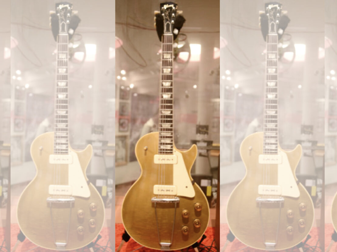A color image showing a gold electric guitar on display.