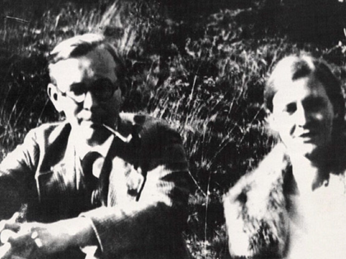 A black and white photograph of Mildred and Arvid. Arvid is on the left and Mildred on the right. They are sitting in a grassy area and looking towards the viewer.
