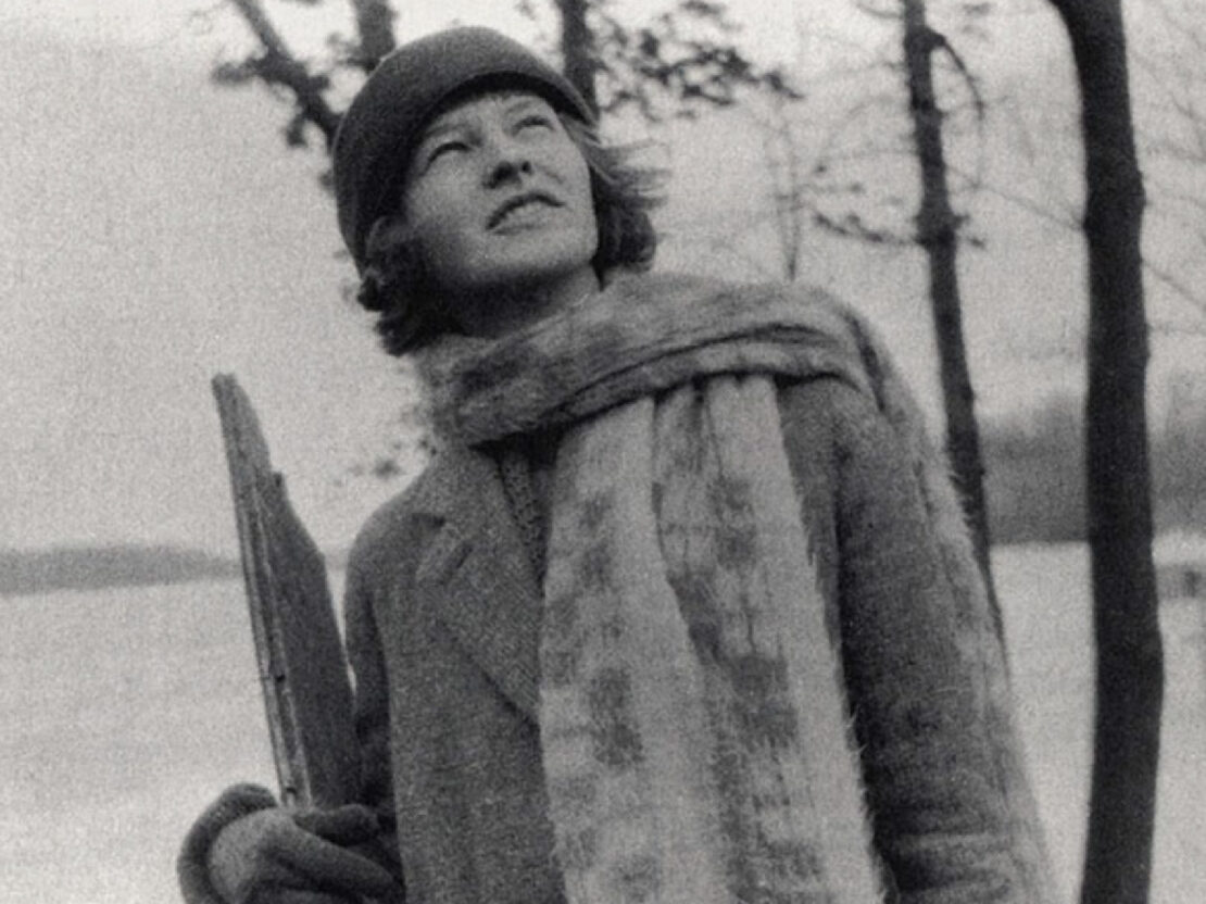 A black and white photograph of Mildred Fish-Harnack. She is standing outside looking up and to the right of the viewer.