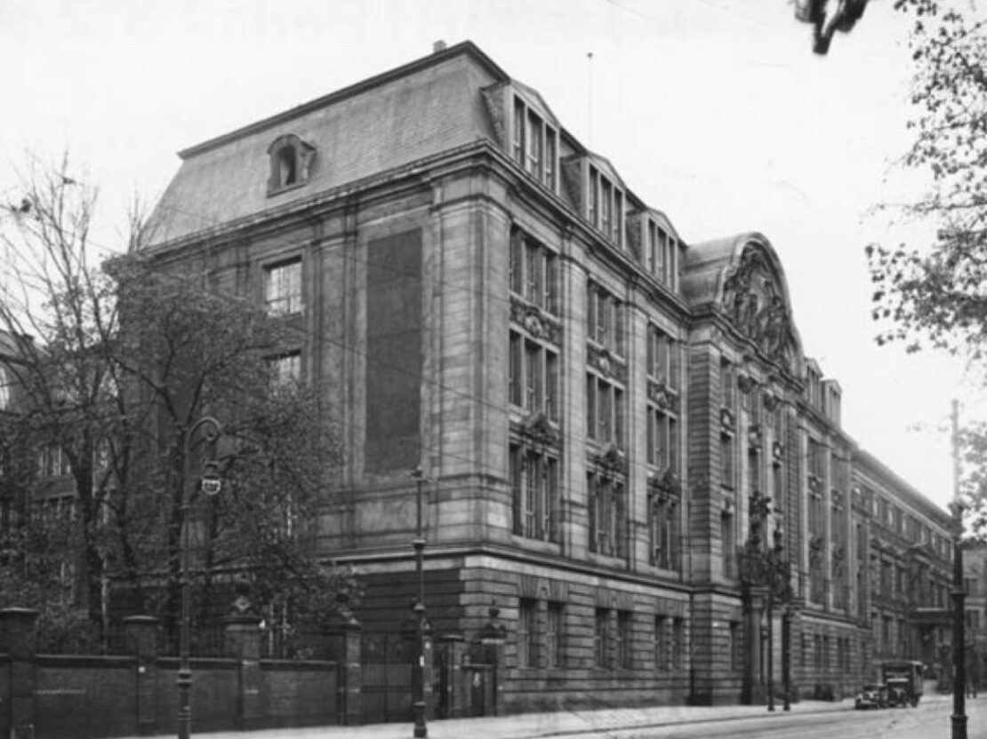 A black and white photograph of a large stone building taken from street level.