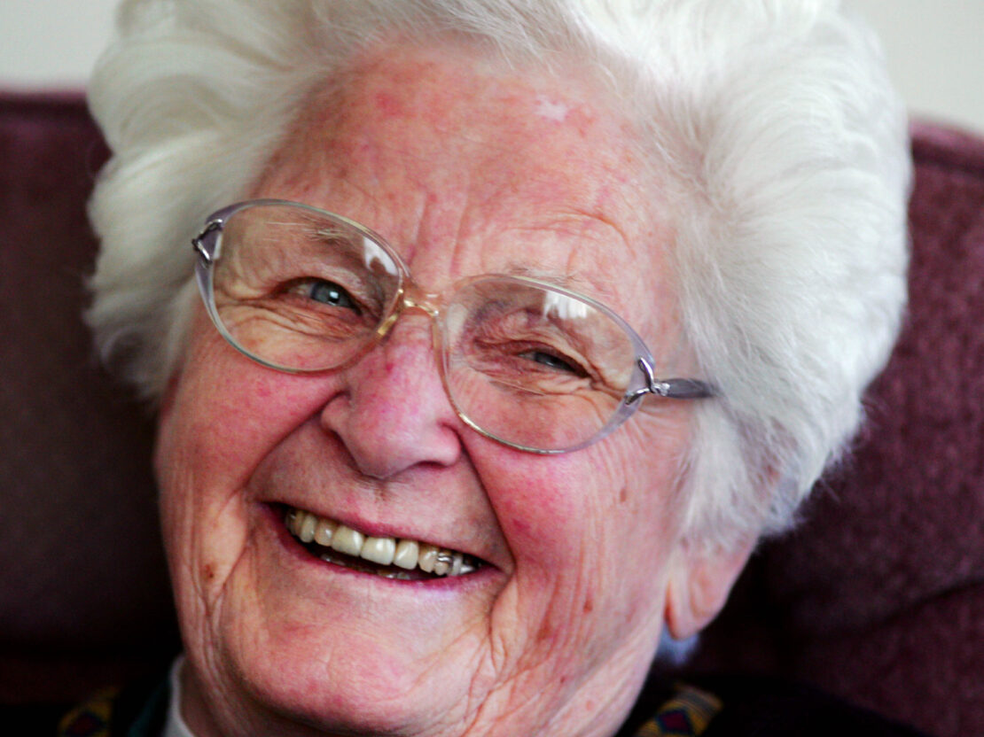A color portrait of older Milly. Her face is visible and she has a large smile on her face.