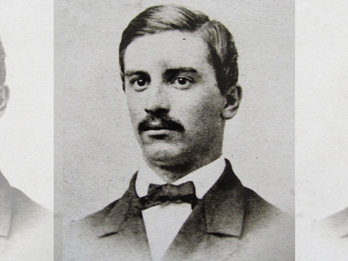 A black and white image of a younger Stephen with dark hair and a mustache. He has a serious expression on his face and looks to the left of the viewer.