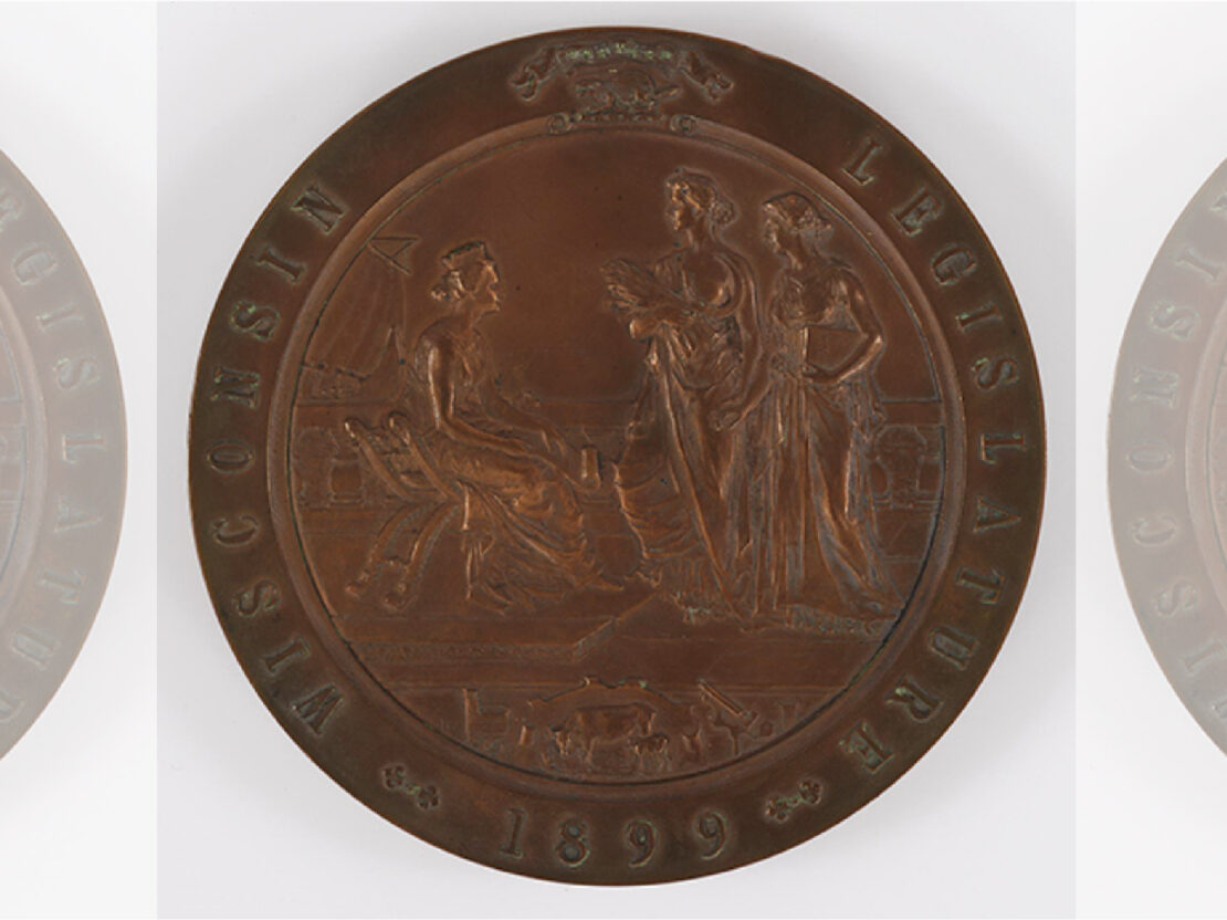 A color image of a bronze medal with people in the center and the words "Wisconsin Legislature 1899" around the outside.
