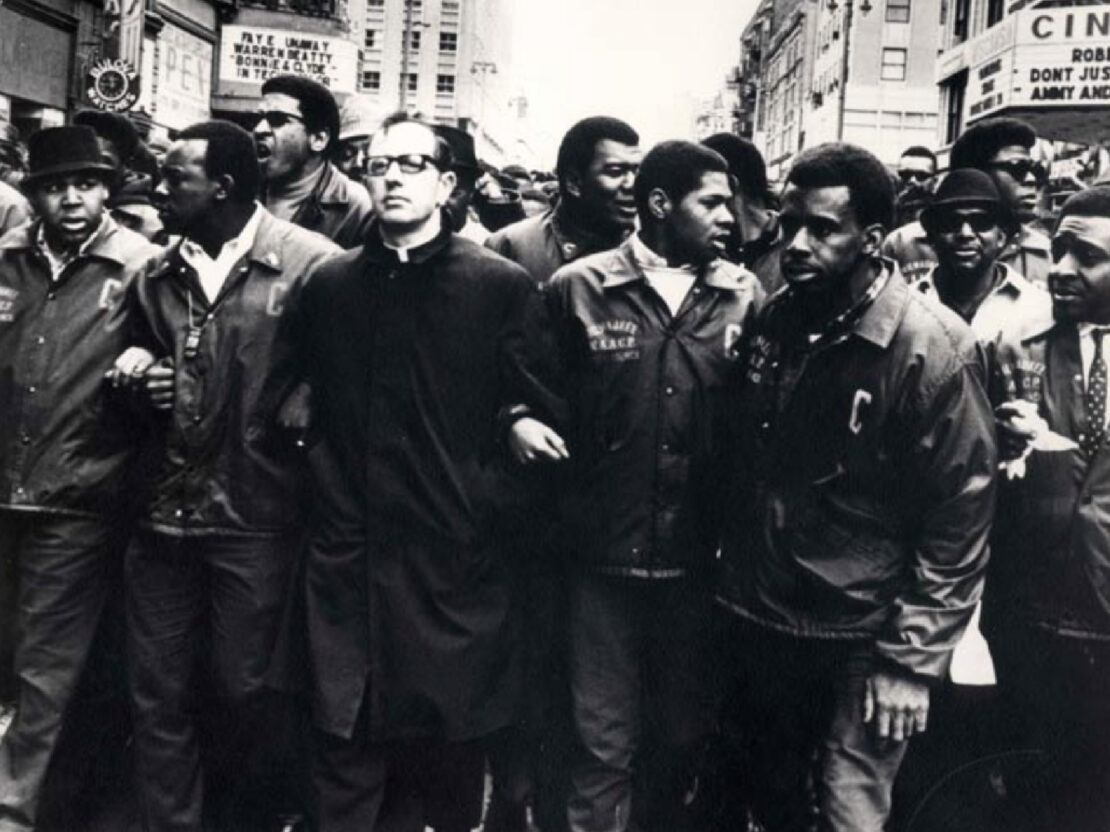 A black and white image of Father Groppi standing with a group of men.