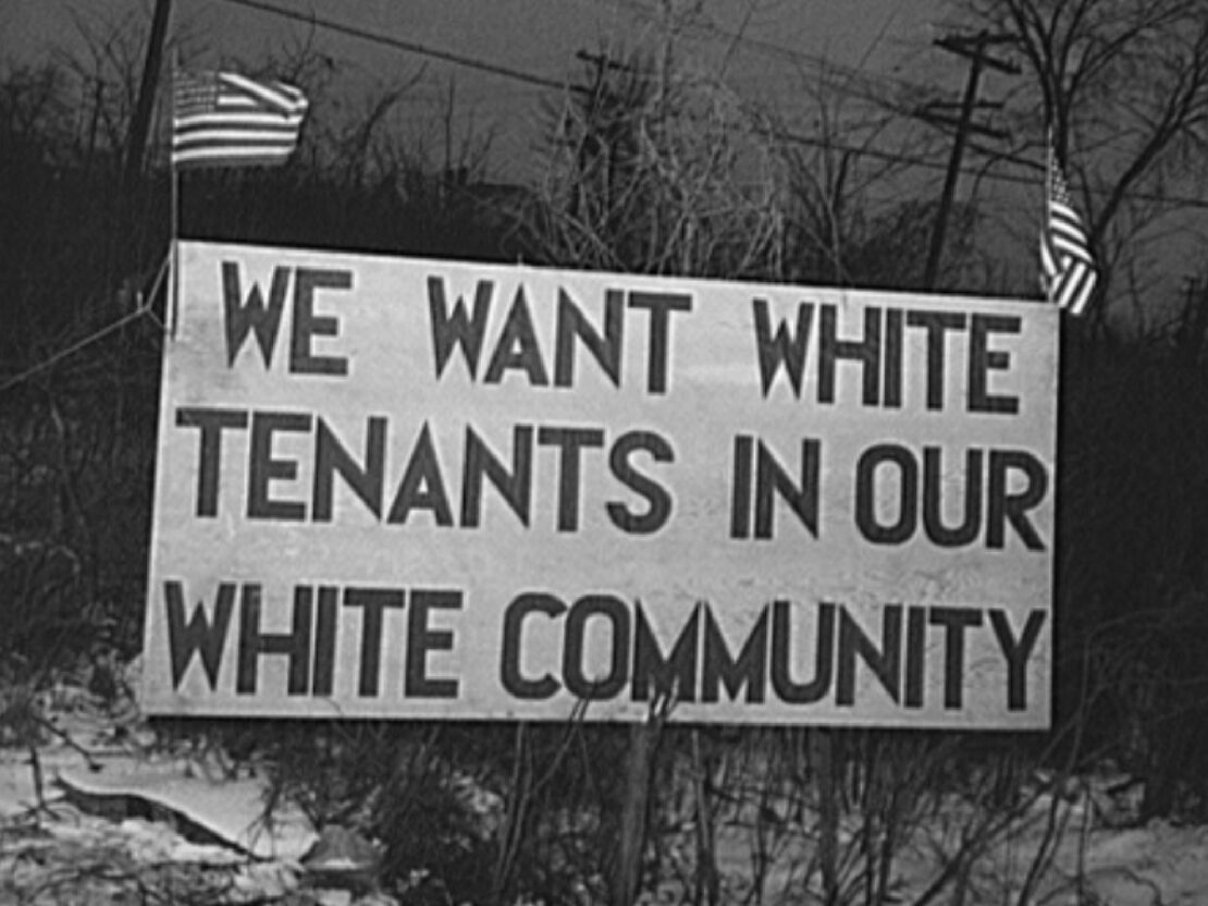 A black and white image of a sign that reads “We want white tenants in our white community.”
