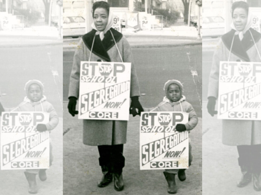 A black and white image of a woman and child standing outside wtih signs that say “Stop School Segregation.”