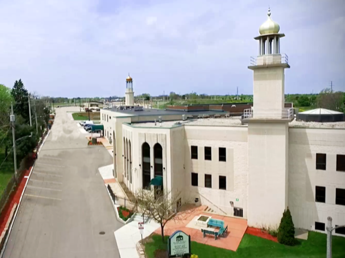 A photograph of a large off-white building. The building has two towers topped with golden domes. There are many windows on the building.
