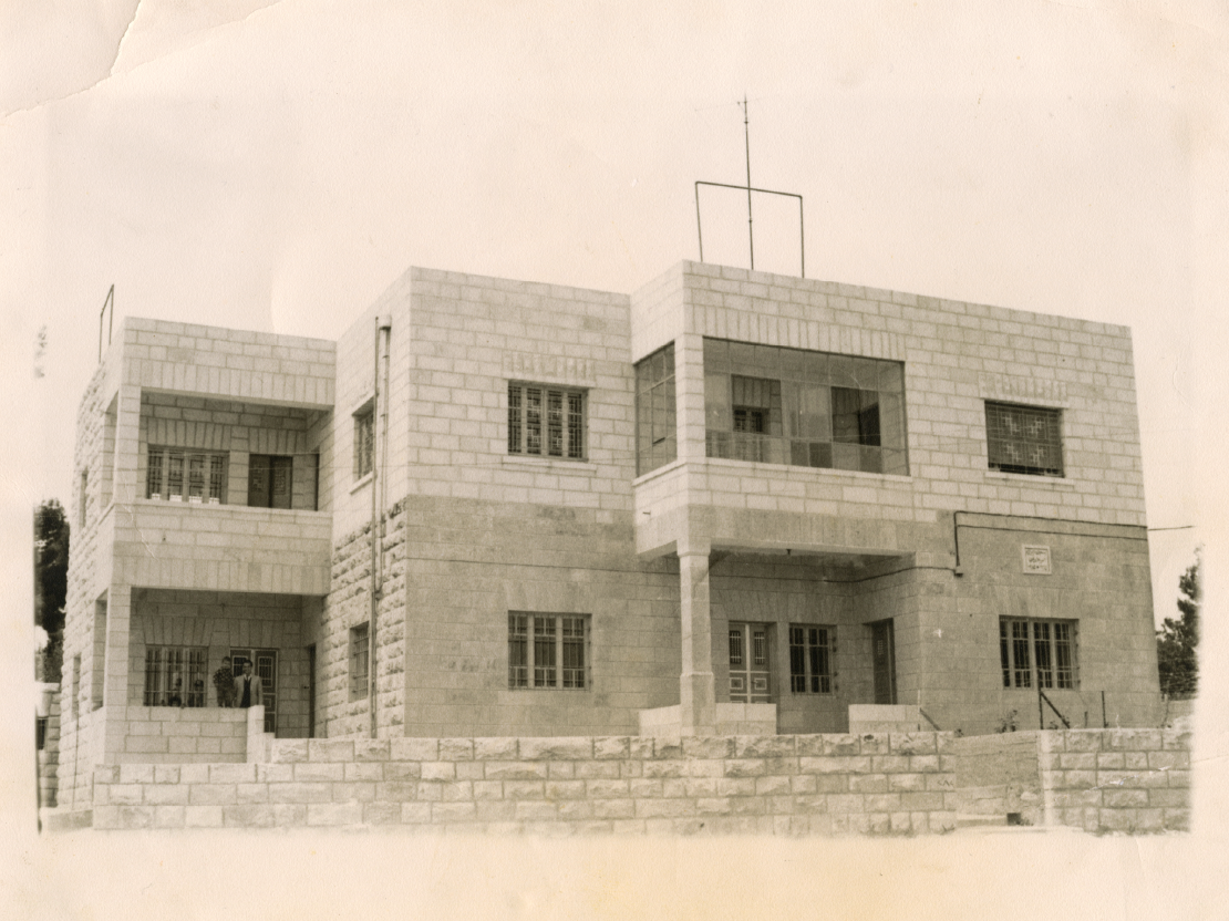 A sepia-toned photograph showing a two-level structure made of stone or concrete blocks, with windows on each side.