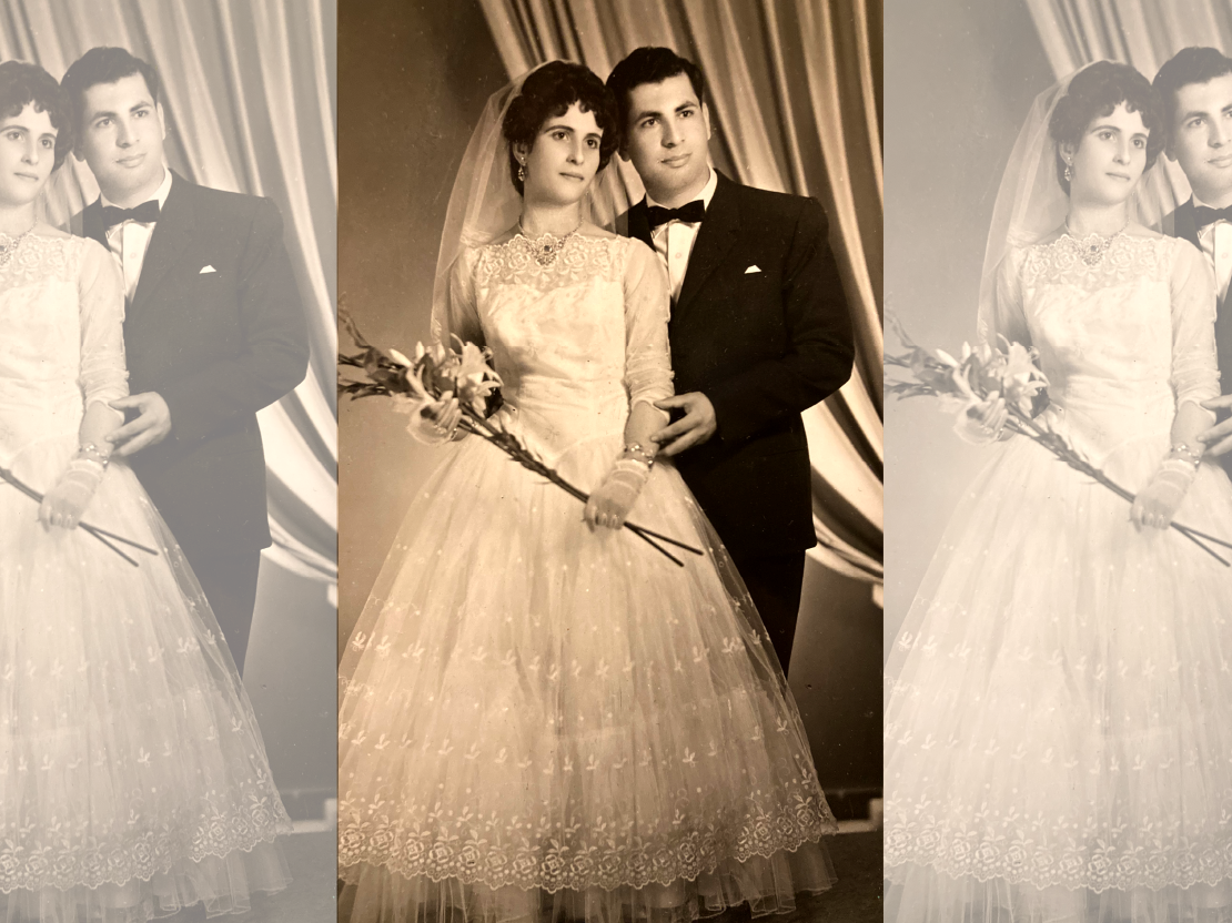 A black and white photograph of Mahmoud and his wife Intisar from their wedding. She is wearing a white wedding dress and holding some flowers. Mahmoud stands slightly behind her and next to her and is wearing a black tuxedo. They both are looking off into the distance.