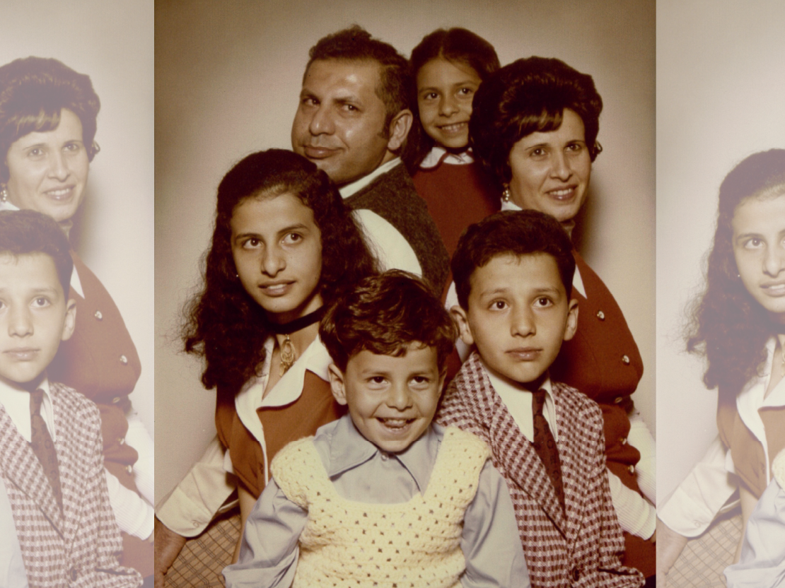 A photograph of the Atta family, with Mahmoud, his wife Intisar, and their four children. The photo is color but sepia-toned due to age. Mahmoud and Intisar sit with their backs to each other and the children are arranged around them.